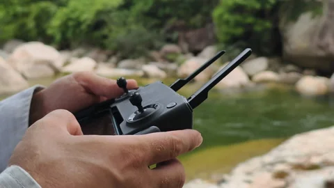 Man operating drone in rocky landscape. Hands hold remote control for man Stock Footage 325022730