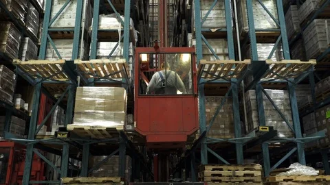 Man operating forklift, lifting and placing stock on shelving in warehouse. 動画素材 88104930