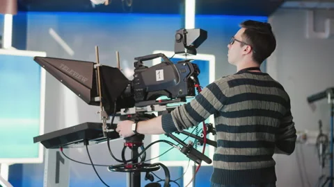 Man operating professional camera rig with teleprompter in broadcast studio Stock Footage 317590206