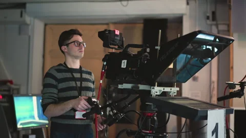 Man operating professional TV camera with teleprompter in broadcast studio Stock Footage 317544522