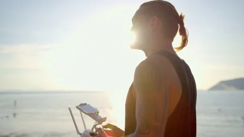 Man operating remote control of drone on beach Stock Footage 74778700