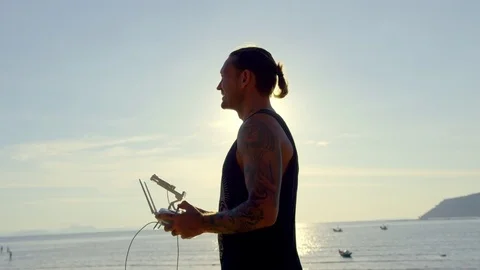 Man operating remote control of drone on beach Stock Footage 74779286