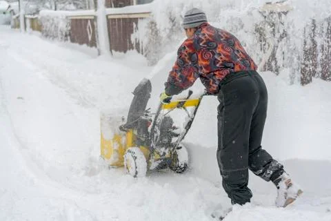 Man operating snow blower to remove snow on driveway. Man using a snowblower. Stock Photos
