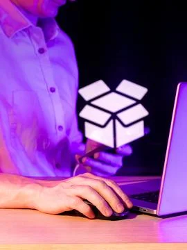 Man operating tech with holographic open box symbol in violet neon glow 스톡 사진