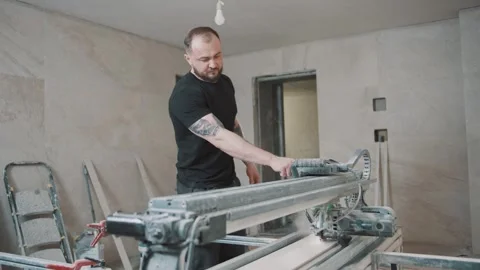 Man operating a tile cutter in a construction environment Video stock 307040649