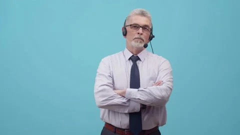 Man operator in headset crosses arms, on studio the blue background. Adult Stock Footage 155432977