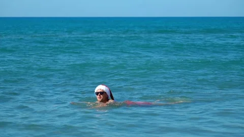 Man or guy in santa claus hat bathing in sea Stock Footage 253392147