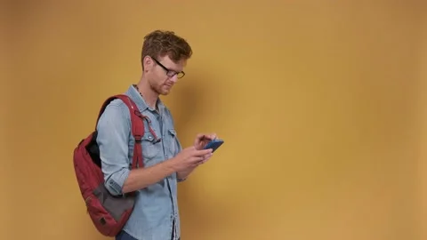 A man on an orange background shows an approving gesture with a phone in his Stock Footage 201156692
