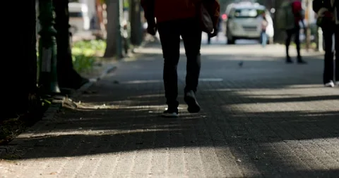 Man in orange coat walking into frame carrying bag on sidewalk toward car, Stock Footage 341241510