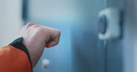 A man in an orange jacket knocks on a metal door. Close-up of a hand. Video stock 206702440