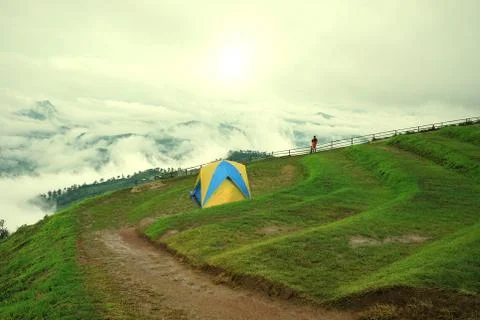 Man in orange jacket looking at view of mountain landscape with waves of fog Stock Photos