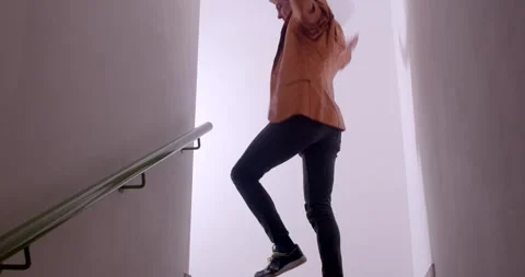 A man in an orange jacket navigates a staircase purposefully Stock-Footage 313564480