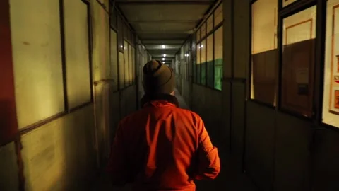A man in an orange jacket walks through the old hallway Stock Footage 233071682