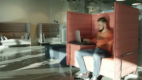 Man in orange pullover working on laptop 库存影片 77282674