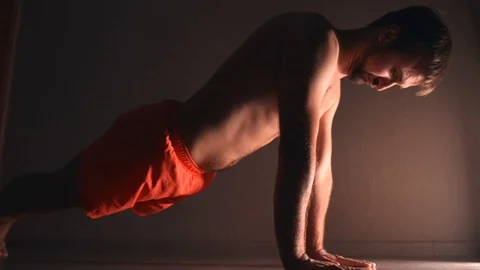 Man in orange shorts try to do plank exercise at home Stock Footage 121323353