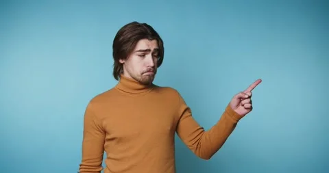 Man in orange sweater shows different emotions with hand gestures against a.. Vídeo Stock 328249927