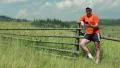 Man in orange t-shirt stands in field and communicate via smartphone HD Footage