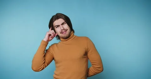 Man in orange turtleneck thinking against blue background Stock Footage 315162928