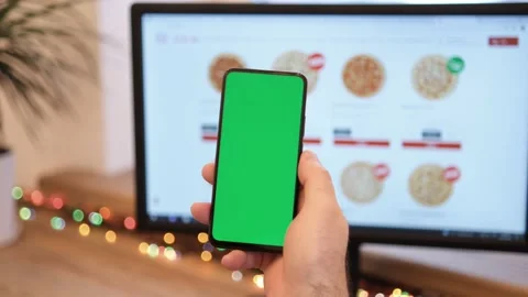 A man orders pizza. Man in office is holding a smartphone with a green screen Stock Footage 170871615