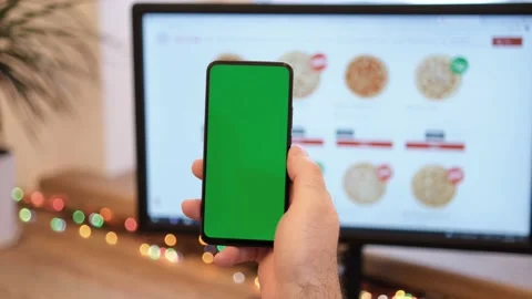 A man orders pizza. Man in office is holding a smartphone with a green screen Stock Footage 172808727