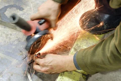 Man in ordinary clothes with angle grinders while working in the workshop cut Stock Photos