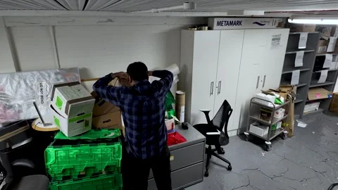 Man Organizing Cardboard Boxes in Office Basement Storage Room Moving and Stock Footage 327830441