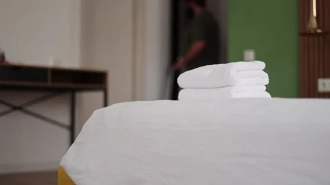 Man out of focus in blue summer shorts checks into hotel room with white towels Stock Footage 329667082