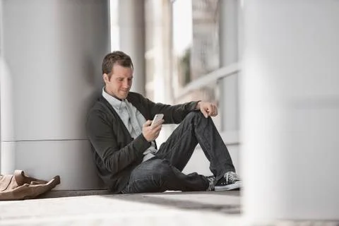 A man outside a building, checking his smart phone. Fotos de archivo