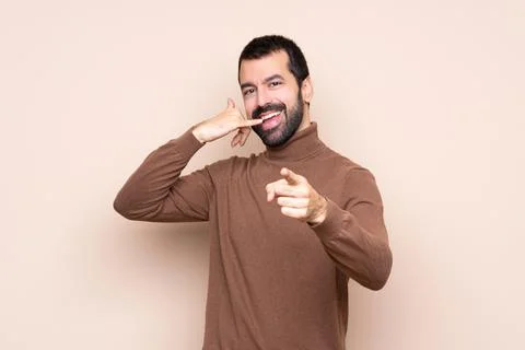 Man over isolated background making phone gesture and pointing front Stock Photos