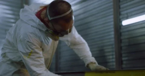 Man in overalls and protective mask paints metal structures with a roller yellow Stock Footage 166879875