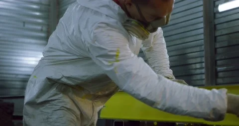 Man in overalls and protective mask paints metal structures with a roller yellow Vidéo 166879984