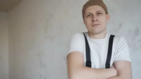 A man in overalls approaches the camera and crosses his arms over his chest Video stock 144570894