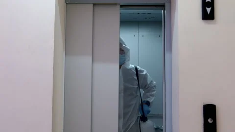 A man in overalls comes out of the elevator to disinfect the room.4K,slow motion Video stock 144489492