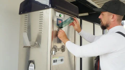 Man in overalls at self-service car wash inserting token into payment machi.. Stock Footage 320888565