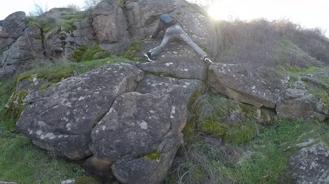 The man overcomes the obstacle climbing over the rock and he opens his way up Stock Footage 127691069