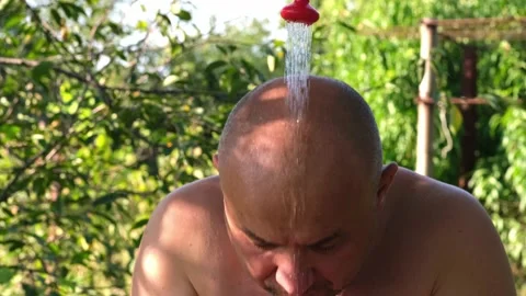 Man is overheated and cooled by stream of cool shower water outside Video stock 206011177