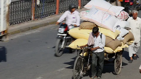 Man overloads a three wheeled bicycle to deliver rice on busy streets in India. Stock Footage 37516617