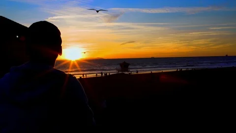 Man overlooking beach at pier during sunset, 4K Stock Footage 101002397