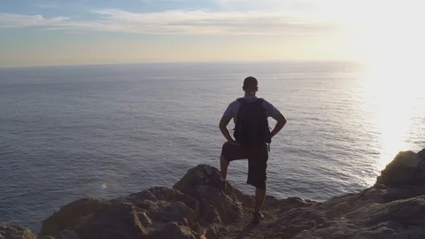 Man overlooking ocean from a cliff, 4k Stock Footage 103438164