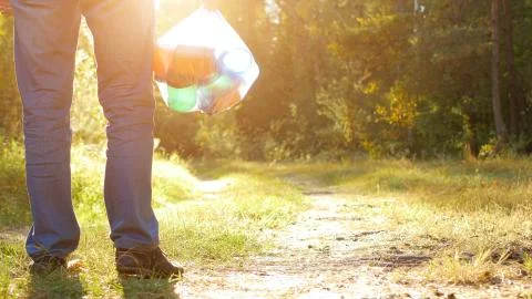 A man with a package of garbage in his hands with plastic in the forest against Foto stock