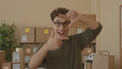 Man with packages frames his face with hands and points at camera while smi.. Stock Footage 337435629