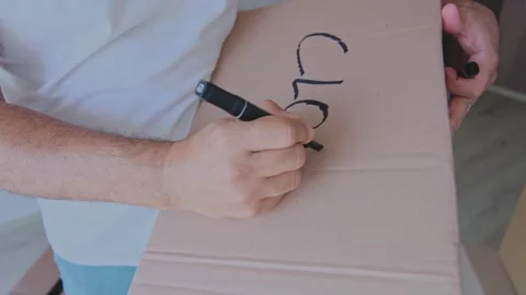 A man is packing boxes and writing clothes on them. New home concept. Stock Footage 315701083