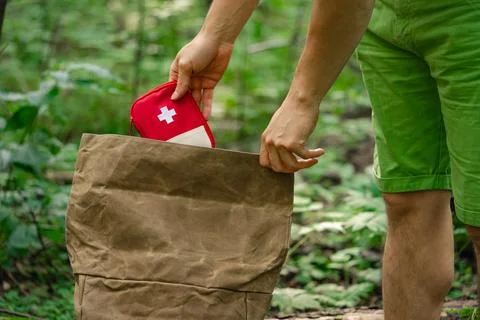 Man Packing First Aid Kit into Backpack While Hiking in Forest Stock Photos