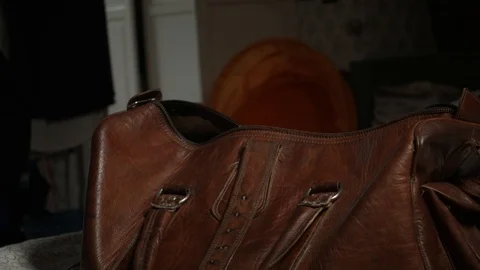 Man packing a leather overnight bag with essentials and walking out of Stock Footage 101971653
