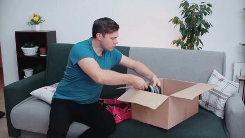 A man is packing a parcel with warm clothes. Stock Footage 145371266