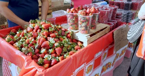 Man packing strawberries into plastic containers at a farmers' market Stock Footage 87775292