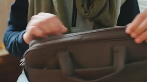 Man packs quickly. Man adjusting briefcase zipper for urban commute preparedness Stockbeeldmateriaal 338435744