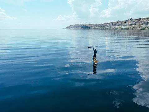 A man with a paddle on a board on a big river Stock Photos