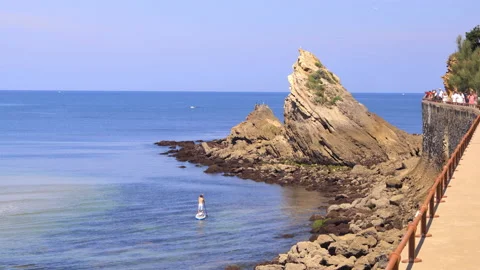 Man paddle boarding on the Atlantic Ocean next to a rock in Biarritz, France Stock Footage 157389701
