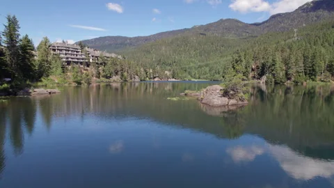 Man paddle boarding on a pristine mountain lake on sunny day with his dog, stand Stock Footage 246611677